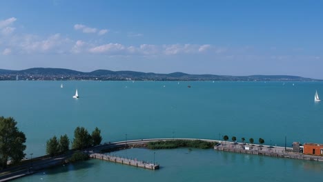 Flying-above-the-pier-at-Tihany,-Lake-Balaton,-Hungary,-with-Balatonfüred-and-the-northern-shores-in-the-Background