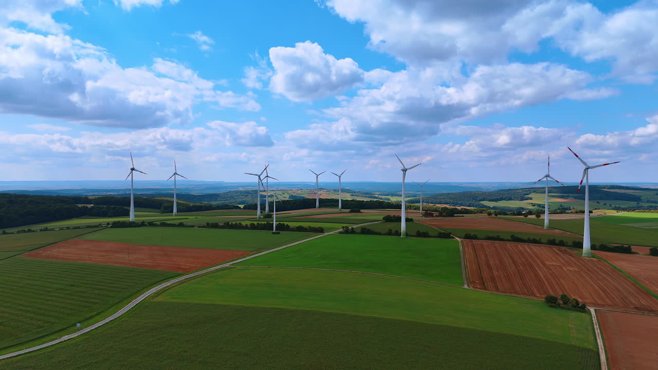 Wind turbines rotating slowly against cloudy sky. Green energy production in the fields. Aerial view