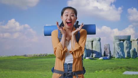 asian female hiker with mountaineering backpack saying wow while traveling in stonehenge