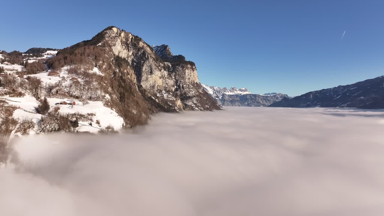 Aerial view of mountains in the Swiss Alps, with mist covering most of the landscape and only the snow-covered peaks visible.