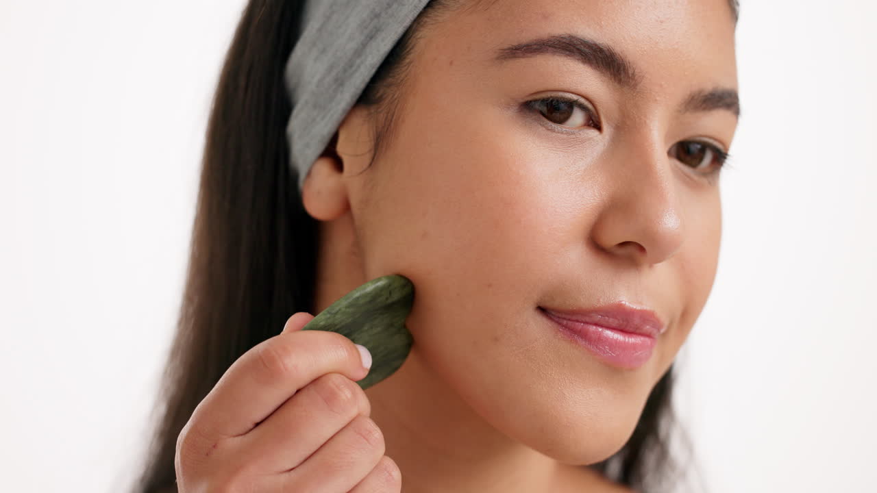 Woman using gua sha tool for facial massage