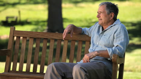 hombre viejo relajándose en un banco y sonriendo a la cámara