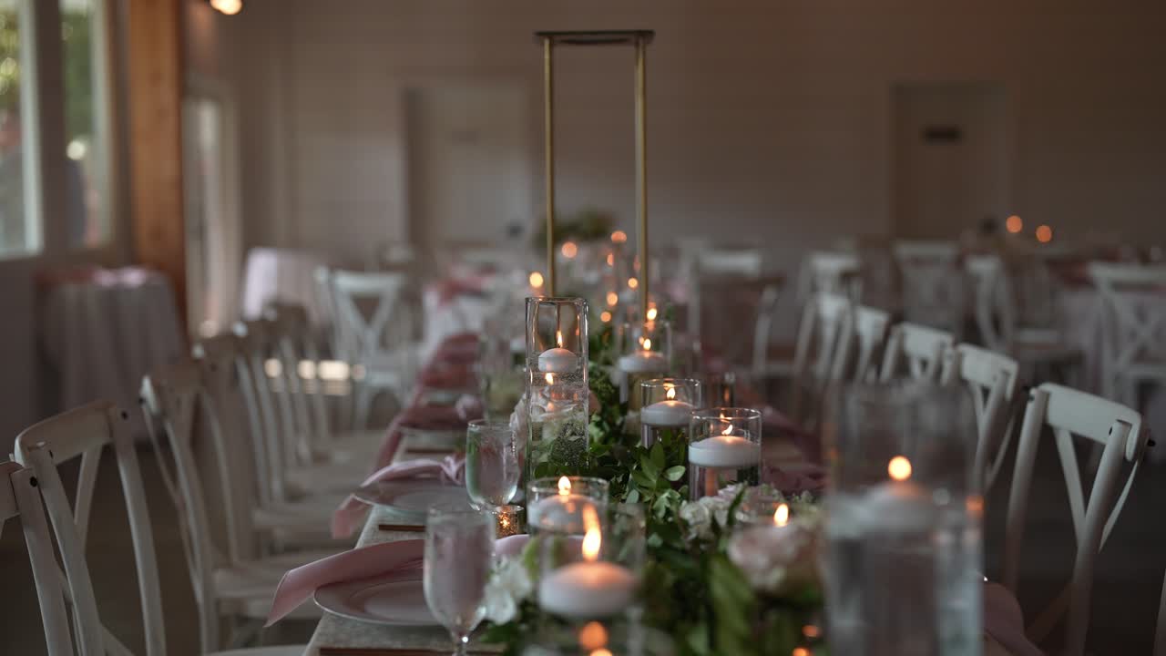 bella sistemazione lungo tavolo per un ricevimento di nozze, adornato con candele delicate, fiori freschi, e tutti i dettagli che contribuiscono ad un ambiente romantico e elegante