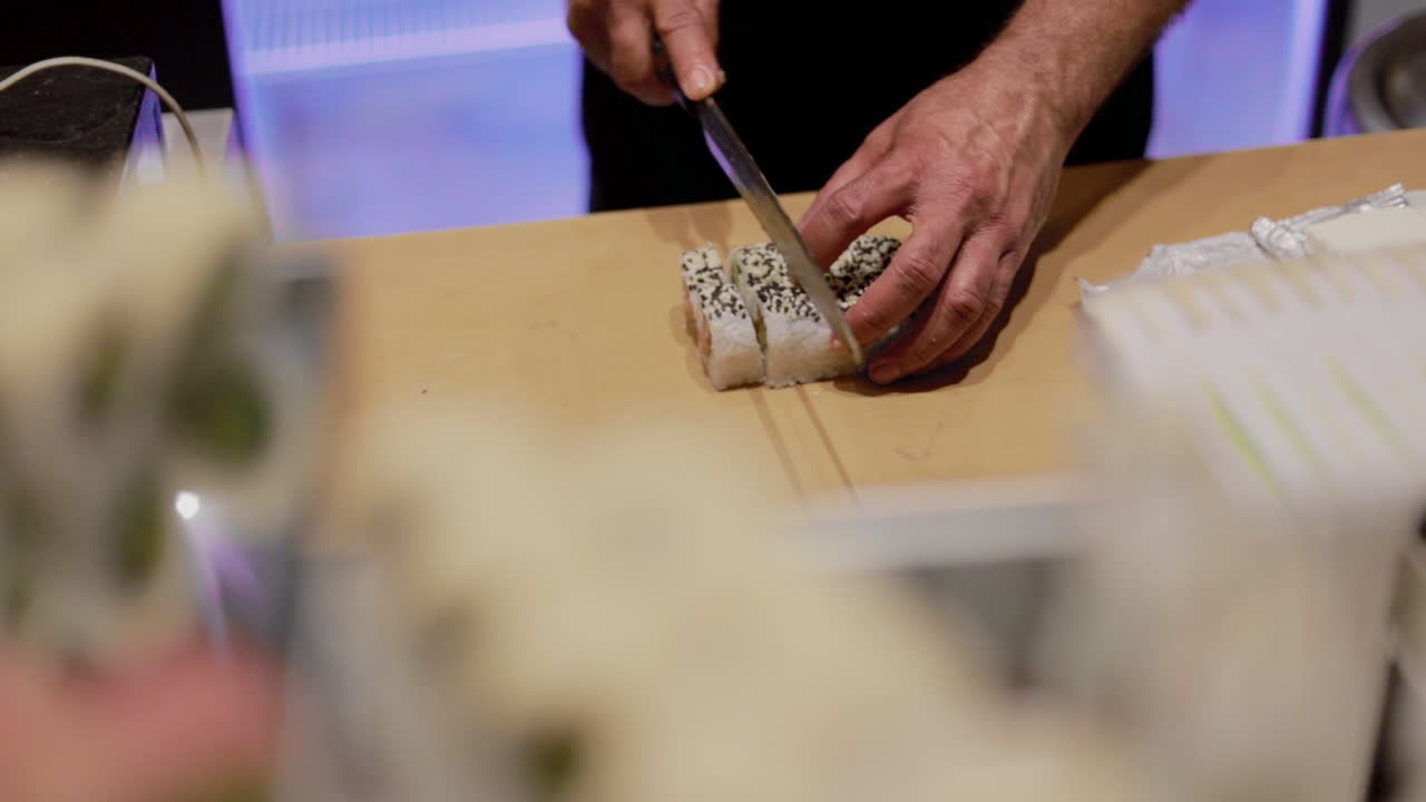 부엌 카운터에서 초밥을 자르는 요리사 손의 하이 앵글 샷