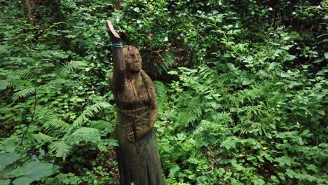 estatua femenina indígena americana decorativa tallada entre la vegetación silvestre cubierta de bosques