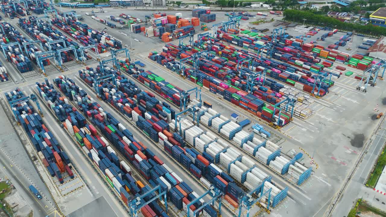 Aerial view of Klang Port container depot in Selangor, Malaysia. Colorful shipping containers stacked in rows, industrial cranes, and busy port logistics hub seen from above. UHD.