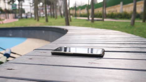 a black phone on a wooden bench in a park