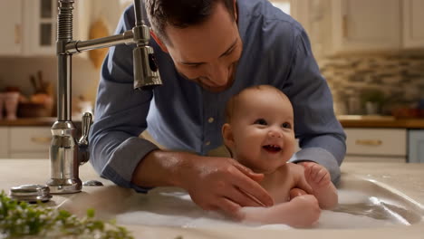 father giving baby a joyful bath in the kitchen sink