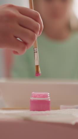 lady takes pink paint with brush to show little girl ebru drawing technique in classroom closeup slow motion. conducting art lesson for child