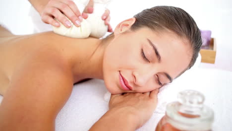 Woman-enjoying-a-herbal-compress-massage