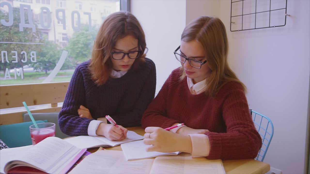dos estudiantes estudiando juntos en un café