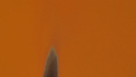 una hoja de papel naranja se quema y fuma en la pantalla azul clave de croma. el fuego quema el papel desde el medio de la hoja y lo convierte en ceniza. perfecto para hermosas transiciones de video. cerca. cámara lenta