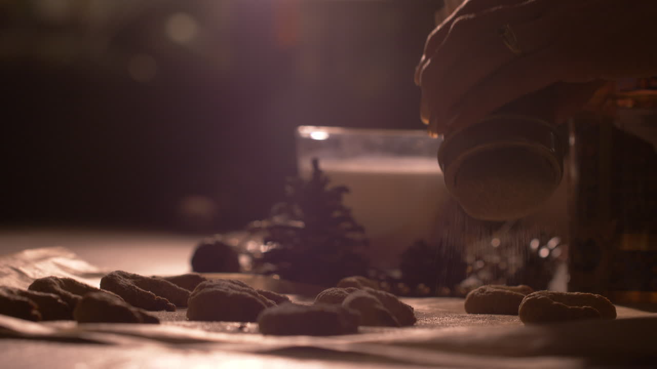 Sprinkling powdered sugar onto cookies pastry on a baking sheet. Close up, no face
