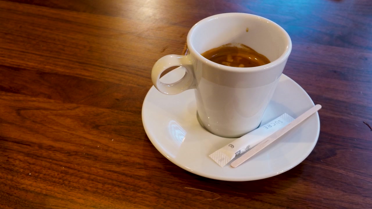 Inquadratura statica dall'alto di caffè espresso con zucchero e paletta su un tavolo di legno