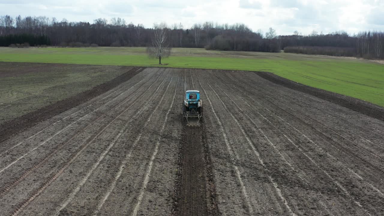 vista aérea desde la parte trasera agricultor conducir con viejo tractor y cultivar el surco de ajo