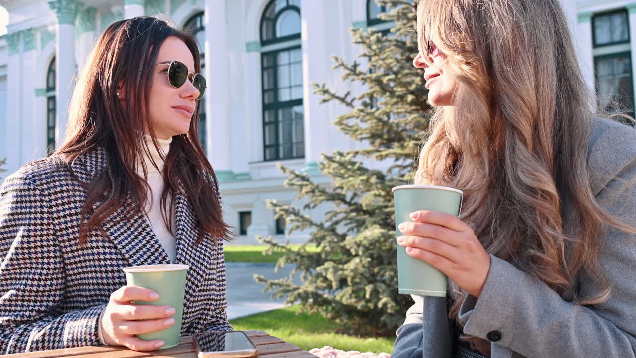 Two women talking and drinking coffee at a terrace