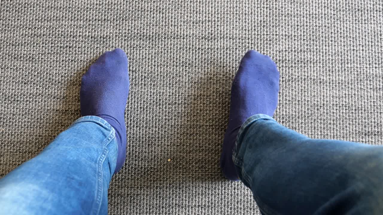 persona de pie en una alfombra con calcetines azules y vaqueros