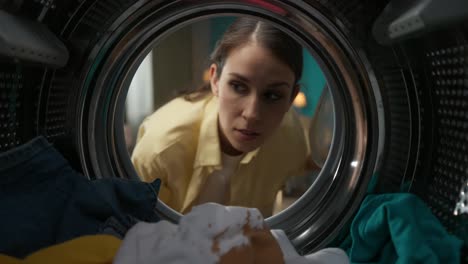 woman checking a stain on a shirt in the washing machine