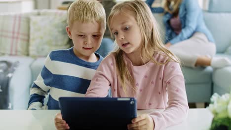 siblings using a tablet in living room