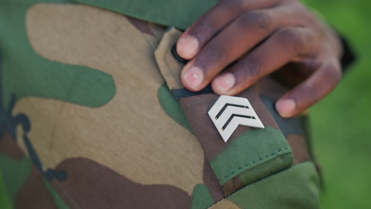 CloseUp Soldier Adjusting Sergeant Chevrons On Camouflage Sleeve, Hand Fingers Resting Near Button And Patch, Soft Natural Light, Shallow Depth Of Field, Quiet Disciplined Moment Conveying Pride