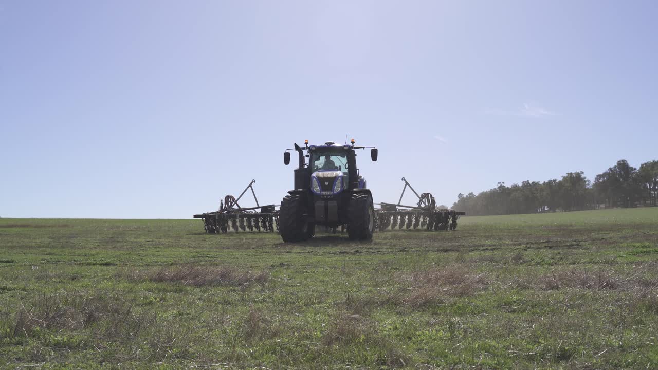 un disparo estacionario de una máquina sembradora de perforación de grano que se acerca a la granja yendo hacia la cámara