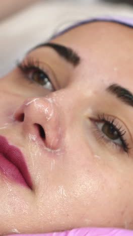 beautiful young woman getting cosmetic mask in spa salon. cosmetic facial treatment. concept of skin care vertical video