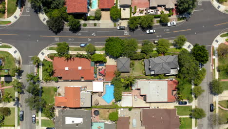 aerial view of a sunny suburban residential neighborhood with houses and swimming pools