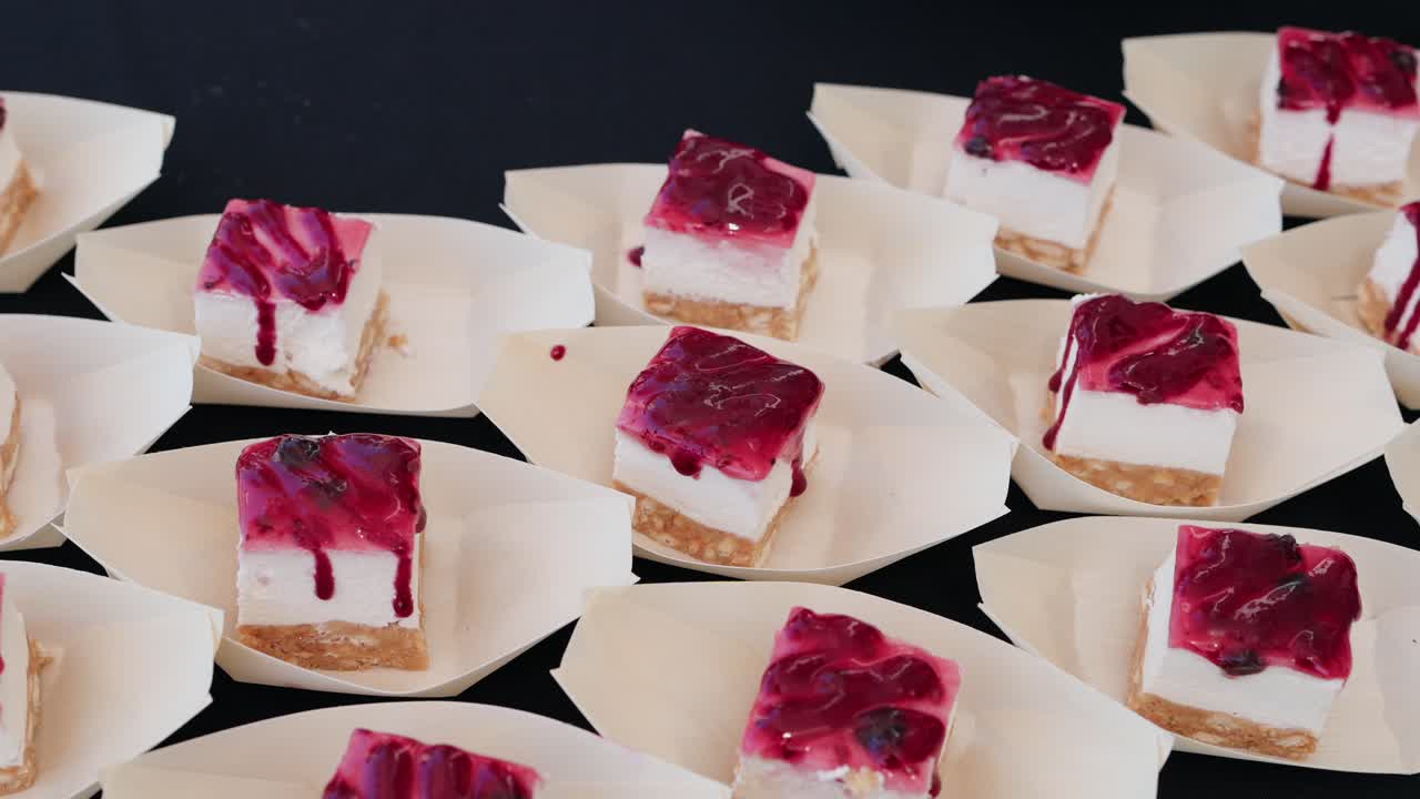 small cheesecake bites with berry topping served in individual paper trays on black background