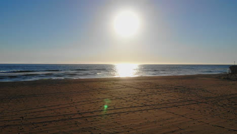 High-fly-in-over-empty-volleyball-net-to-beautiful-sunset-beach-scene-with-lifeguard-tower-in-Southern-California--aerial-drone-4k