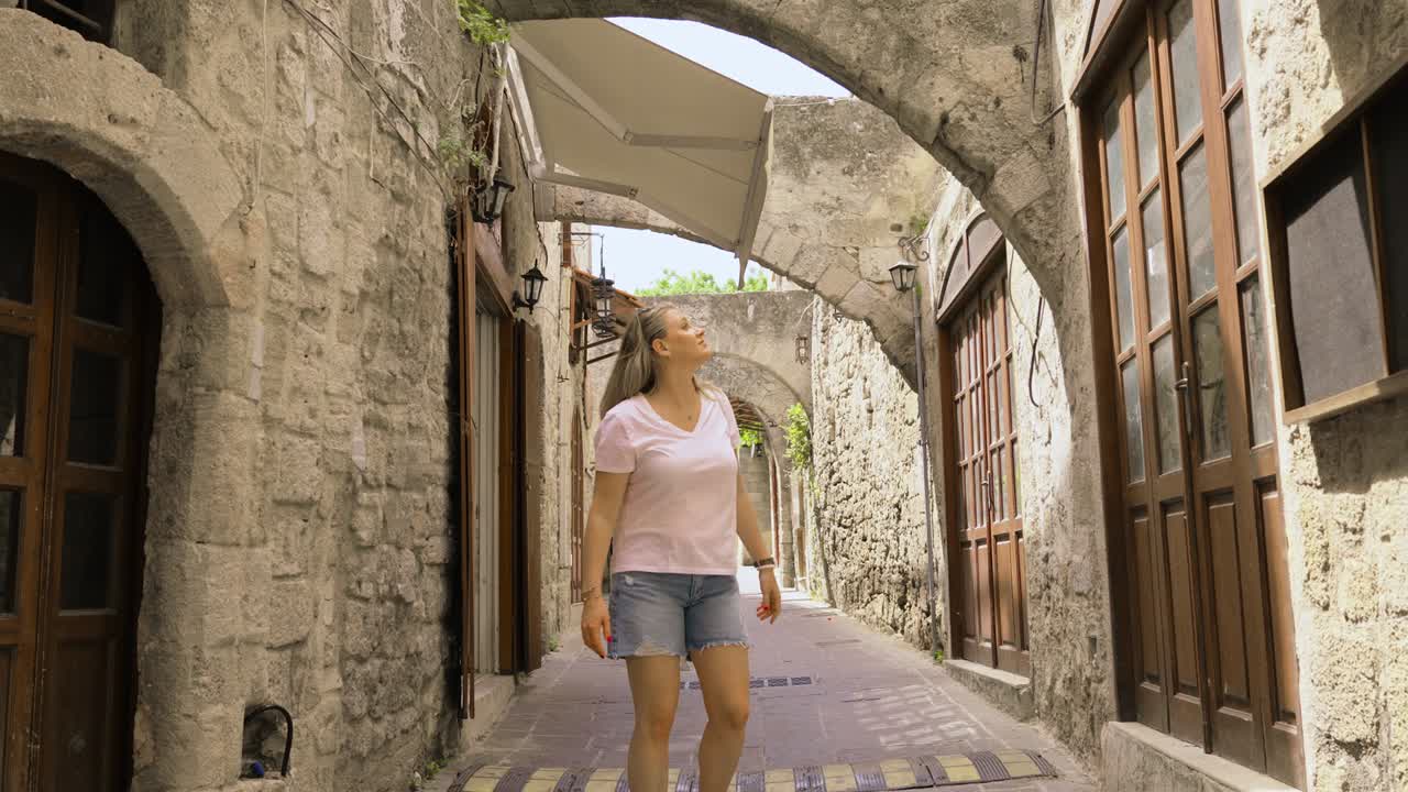 Donna che esplora una vecchia e stretta strada medievale caratterizzata da archi in pietra e una strada acciottolata