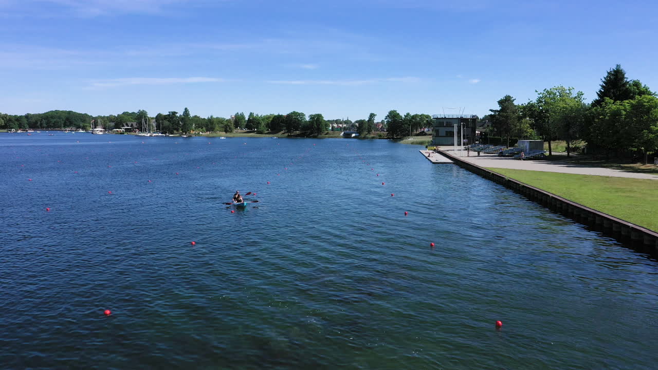 AERIAL: Tired Athletes in Canoe Sails Towards the Shore Across Buoy Marked Lines