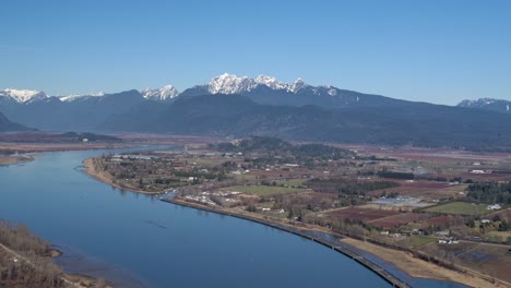 Broad-River-with-Snow-Capped-Mountains-in-Distance---Sunny-Day-Aerial