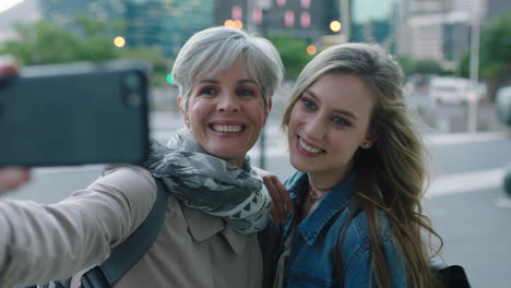 portrait of beautiful mother and daughter posing taking selfie photo using smartphone camera technology enjoying hanging out together