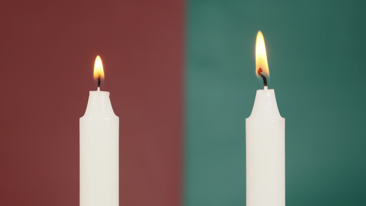 Due candele accese su uno sfondo rosso e verde nelle vicinanze. Spegnere le candele.