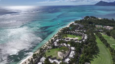 aerial view of a tropical beach resort with turquoise ocean and golf course