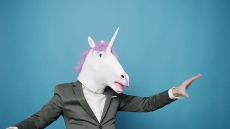 happy guy in gray suits he is having fun with unicorn mask. fool's day