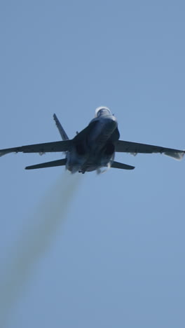 vertical video of military jet aircraft flying up with visible vapor condensation caused by pressure difference in slow motion