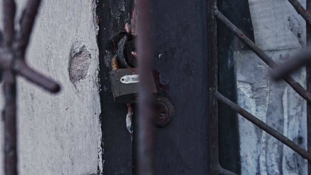 puerta vieja y dañada del edificio abandonada durante la crisis económica asegurada con un candado y un llave oxidados