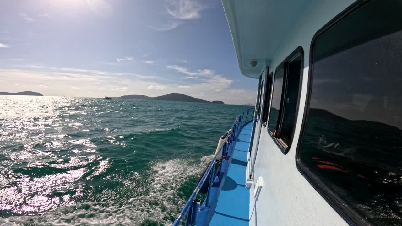 A tranquil boat ride on clear waters near Phuket, Thailand. Bright sunlight, gentle waves, and distant islands create a peaceful atmosphere