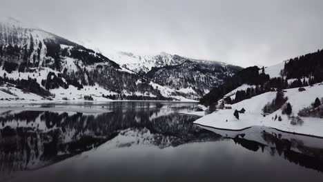 Increíble-Hermoso-Vuelo-De-Cámara-Sobre-Un-Lago-De-Montaña-Reflectante-En-El-Invierno-En-Suiza