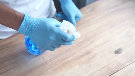 cleaning a wooden table with disinfectant spray