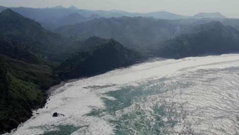 Antena-De-Olas-Espumosas-Blancas-Rompiendo-En-La-Playa-Menganti-En-Java-Central,-Indonesia