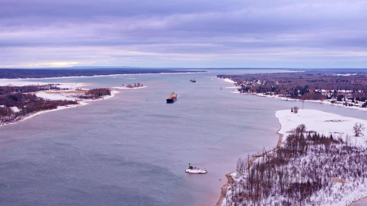 St. Mary Nehri üzerinde uçan drone görüntüleri, karlı bir Kuzey Michigan manzarası ortasında Soo Kilitleri'ne doğru ilerleyen bir yük gemisini gözler önüne seriyor.