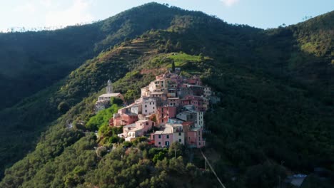 small village on the slope of mountain range with houses in wide range of color, drone tracking shot