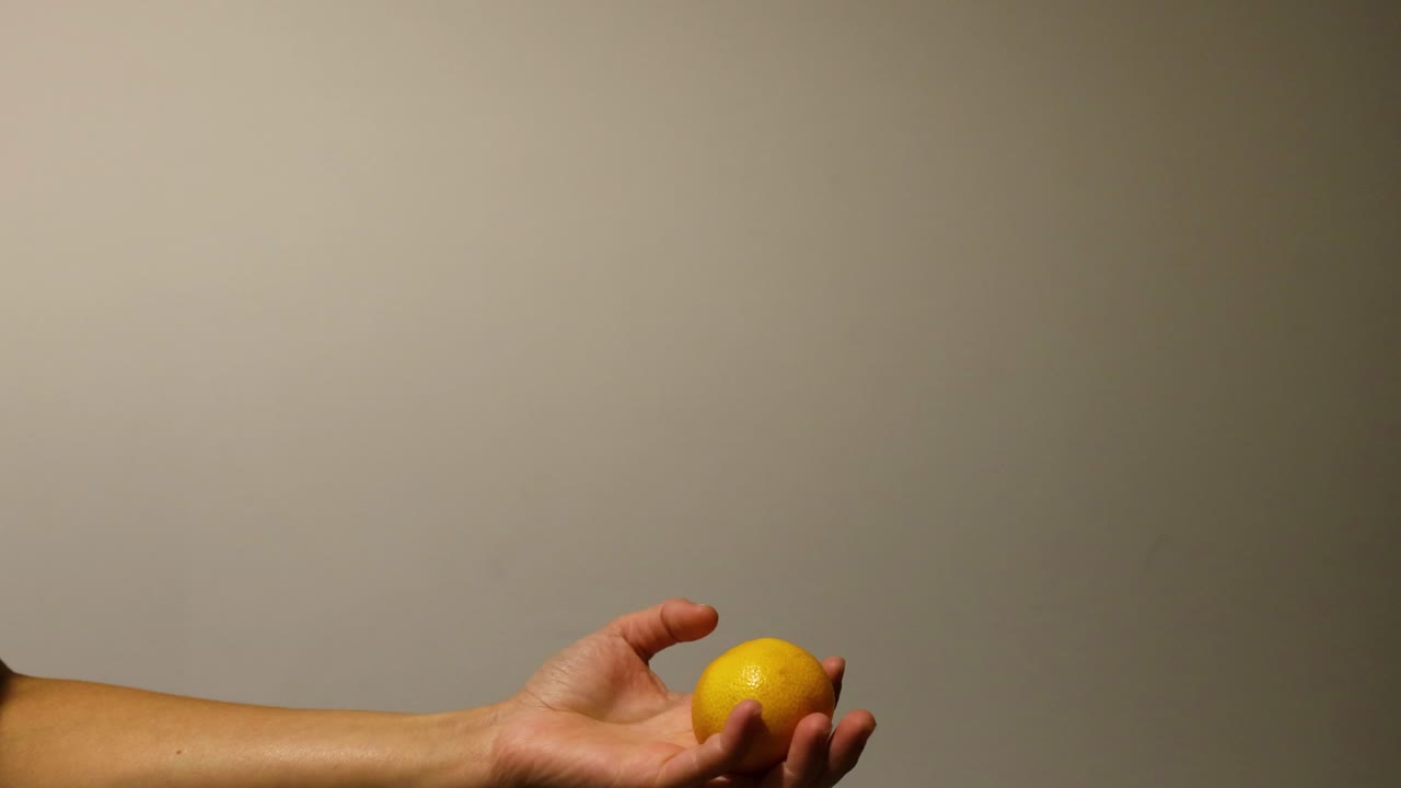 una mano lanza y atrapa una naranja