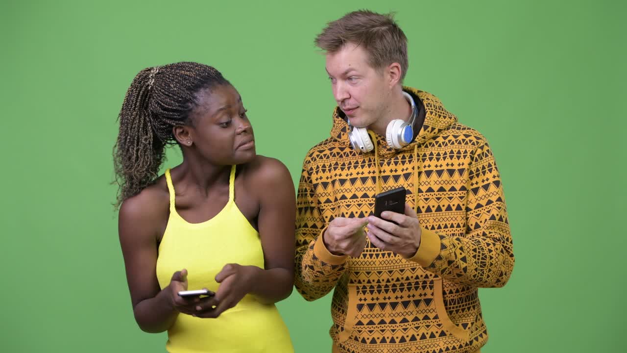 una joven pareja multiétnica usando el teléfono juntos.