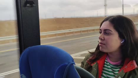 a woman is sitting on a bus with her earbuds in