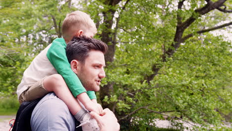 slow motion shot of father carrying son on shoulders on walk in countryside