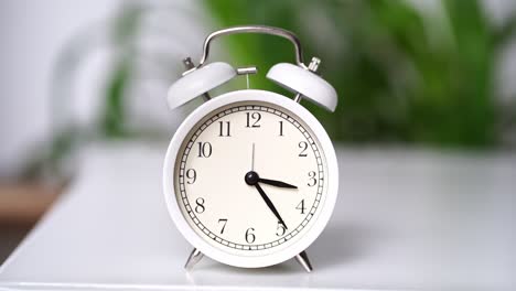 las agujas en el dial del despertador blanco se mueven rápido.