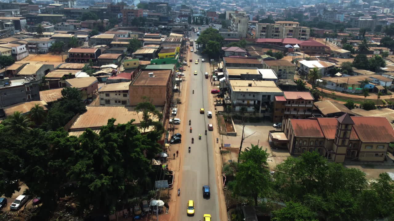 Ripresa con drone che si inclina sul traffico nella soleggiata città suburbana di Yaoundé, Camerun, Africa.